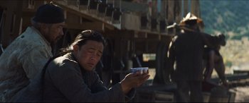 Movie still from “Seraphim Falls” (2006), directed by David Von Ancken – A man holding a cell phone in his hands; Medium shot, Over the shoulder angle