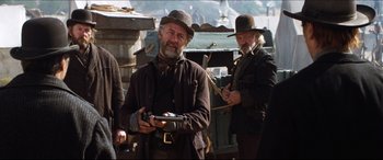 Movie still from “Seraphim Falls” (2006), directed by David Von Ancken – A man holding a gun while standing next to another man; Medium shot, Low angle