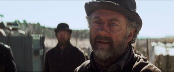 Movie still from “Seraphim Falls” (2006), directed by David Von Ancken – A man with a beard wearing a hat and a jacket; Close Up shot, Over the shoulder angle