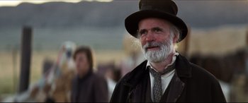 Movie still from “Seraphim Falls” (2006), directed by David Von Ancken – An old man with a beard wearing a hat and a tie; Close Up shot, Over the shoulder angle