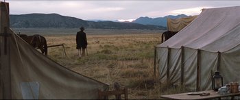 Movie still from “Seraphim Falls” (2006), directed by David Von Ancken – A man in a hat and a coat is standing in a field; Extreme Wide shot, Over the shoulder angle