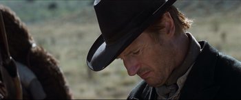 Movie still from “Seraphim Falls” (2006), directed by David Von Ancken – A man wearing a cowboy hat looking down; Close Up shot, Over the shoulder angle