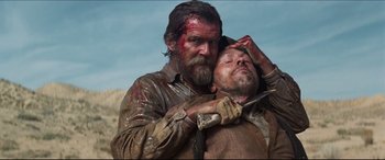 Movie still from “Seraphim Falls” (2006), directed by David Von Ancken – A man holding another man with a knife in his hand; Medium shot, Low angle
