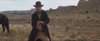 Movie still from “Seraphim Falls” (2006), directed by David Von Ancken – A man holding a gun while standing in a field; Medium shot, Low angle
