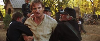 Movie still from “Seraphim Falls” (2006), directed by David Von Ancken – A man being held down by two other men in a crowd; Close Up shot, Over the shoulder angle