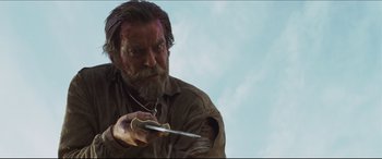 Movie still from “Seraphim Falls” (2006), directed by David Von Ancken – A bearded man holding a knife in his hand; Medium shot, Low angle