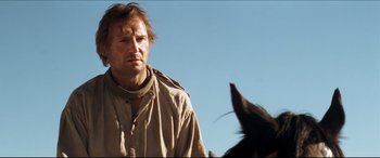 Movie still from “Seraphim Falls” (2006), directed by David Von Ancken – A man standing next to a horse in a field; Close Up shot, Low angle
