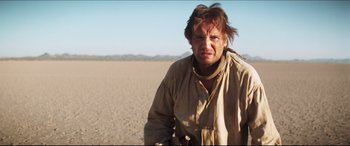 Movie still from “Seraphim Falls” (2006), directed by David Von Ancken – A man with a beard is standing in the middle of the desert; Close Up shot, Low angle