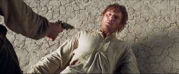 Movie still from “Seraphim Falls” (2006), directed by David Von Ancken – A man laying on the ground holding a gun; Close Up shot, Over the shoulder angle