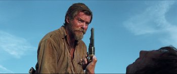 Movie still from “Seraphim Falls” (2006), directed by David Von Ancken – A man with a beard holding a gun in his hand; Medium shot, Low angle