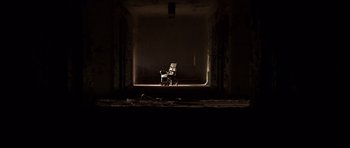 Movie still from “Session 9” (2001), directed by Brad Anderson – An empty chair in the dark in a room; Extreme Wide shot, Low angle