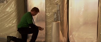 Movie still from “Session 9” (2001), directed by Brad Anderson – A man kneeling down next to an object in a room; Medium shot, Low angle