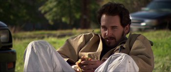 Movie still from “Session 9” (2001), directed by Brad Anderson – A man sitting on the ground eating a piece of pizza; Close Up shot, High angle