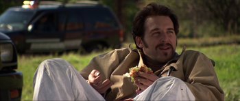 Movie still from “Session 9” (2001), directed by Brad Anderson – A man sitting on the ground eating a sandwich; Medium shot, Over the shoulder angle