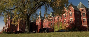 Movie still from “Session 9” (2001), directed by Brad Anderson – A red brick building with a tree in front of it; Extreme Wide shot, Low angle