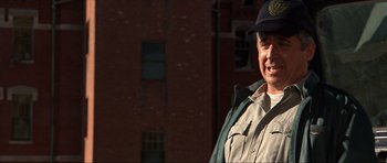 Movie still from “Session 9” (2001), directed by Brad Anderson – A man wearing a hat standing in front of a building; Close Up shot, Low angle