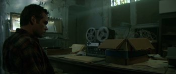 Movie still from “Session 9” (2001), directed by Brad Anderson – An old projector sitting on top of a table; Medium shot, Low angle