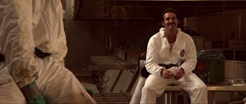 Movie still from “Session 9” (2001), directed by Brad Anderson – A man sitting on top of a chair in front of a building; Medium shot, Low angle