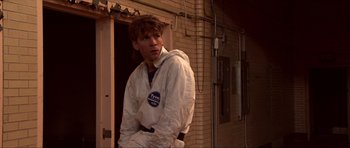 Movie still from “Session 9” (2001), directed by Brad Anderson – A man in a white jacket is leaning against a wall; Medium shot, Low angle