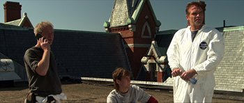 Movie still from “Session 9” (2001), directed by Brad Anderson – Two people sitting in front of a building; Medium shot, Low angle