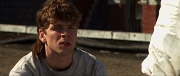 Movie still from “Session 9” (2001), directed by Brad Anderson – A young man sitting on the side of a road; Close Up shot, Low angle