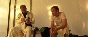 Movie still from “Session 9” (2001), directed by Brad Anderson – Two men sitting on a bench in a room; Medium shot, Over the shoulder angle