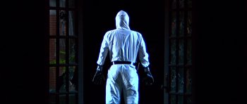 Movie still from “Session 9” (2001), directed by Brad Anderson – A man in a white suit is standing in front of a door; Medium shot, Low angle