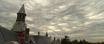 Movie still from “Session 9” (2001), directed by Brad Anderson – A cloudy sky over a row of rooftops; Extreme Wide shot, Low angle