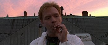 A man is smoking a cigarette while wearing a white jacket