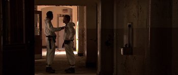 Movie still from “Session 9” (2001), directed by Brad Anderson – Two men in white uniforms standing next to each other in a room; Wide shot, Low angle
