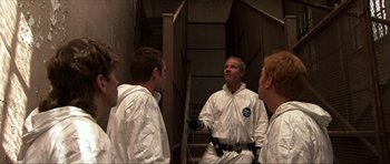 Movie still from “Session 9” (2001), directed by Brad Anderson – A group of men in white coveralls standing next to each other; Medium shot, Low angle