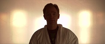 Movie still from “Session 9” (2001), directed by Brad Anderson – A man in a white jacket standing in front of a wall; Medium shot, Over the shoulder angle