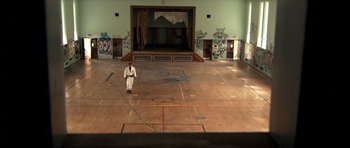 Movie still from “Session 9” (2001), directed by Brad Anderson – A man in a white robe standing in a gym; Extreme Wide shot, High angle