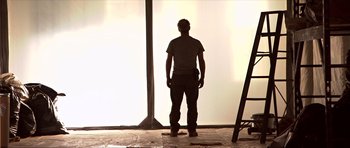 Movie still from “Session 9” (2001), directed by Brad Anderson – A man standing in front of a window in a room; Medium shot, Low angle