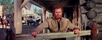 Movie still from “Seven Brides for Seven Brothers” (1954), directed by Stanley Donen – A red headed man leaning on a wooden fence; Medium shot, Low angle