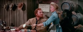Movie still from “Seven Brides for Seven Brothers” (1954), directed by Stanley Donen – A man and a woman are cooking in a kitchen; Medium shot, Over the shoulder angle