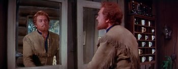 Movie still from “Seven Brides for Seven Brothers” (1954), directed by Stanley Donen – A man with red hair is looking in the mirror; Medium shot, Over the shoulder angle
