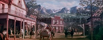 Movie still from “Seven Brides for Seven Brothers” (1954), directed by Stanley Donen – A painting of a town with a horse and carriage in the foreground; Extreme Wide shot, Low angle