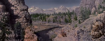 Movie still from “Seven Brides for Seven Brothers” (1954), directed by Stanley Donen – A river running through the middle of a valley with mountains in the background; Extreme Wide shot, High angle