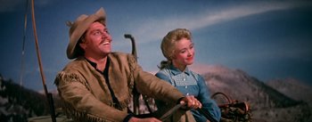 Movie still from “Seven Brides for Seven Brothers” (1954), directed by Stanley Donen – A man and a woman sitting next to each other; Medium shot, Low angle