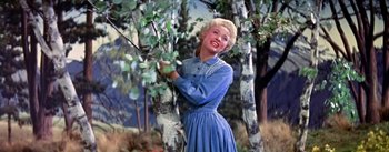 Movie still from “Seven Brides for Seven Brothers” (1954), directed by Stanley Donen – A woman standing next to a bunch of trees; Medium shot, Low angle