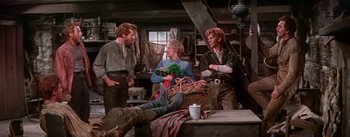 Movie still from “Seven Brides for Seven Brothers” (1954), directed by Stanley Donen – A group of people standing around a table; Wide shot, High angle