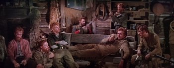 Movie still from “Seven Brides for Seven Brothers” (1954), directed by Stanley Donen – A group of men sitting on top of a wooden bench; Wide shot, High angle