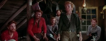 Movie still from “Seven Brides for Seven Brothers” (1954), directed by Stanley Donen – A group of men sitting next to each other; Medium shot, High angle