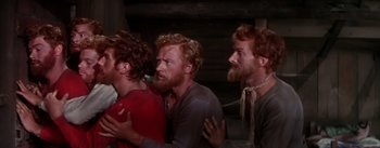 Movie still from “Seven Brides for Seven Brothers” (1954), directed by Stanley Donen – A group of men standing next to each other in a room; Medium shot, High angle