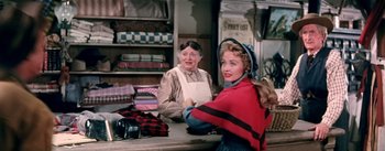 Movie still from “Seven Brides for Seven Brothers” (1954), directed by Stanley Donen – Two women are sitting at a counter in a store; Medium shot, Over the shoulder angle