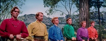 Movie still from “Seven Brides for Seven Brothers” (1954), directed by Stanley Donen – A group of men standing next to each other in front of a tree; Medium shot, Low angle
