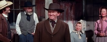 Movie still from “Seven Brides for Seven Brothers” (1954), directed by Stanley Donen – A man wearing a hat and a brown coat; Medium shot, Low angle