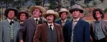 Movie still from “Seven Brides for Seven Brothers” (1954), directed by Stanley Donen – A group of men standing next to each other wearing hats; Medium shot, Low angle