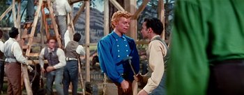 Movie still from “Seven Brides for Seven Brothers” (1954), directed by Stanley Donen – Two men are talking in front of a building; Medium shot, Over the shoulder angle